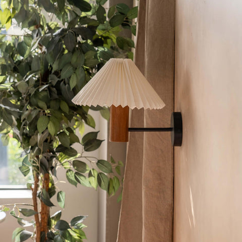 White pleated shade wall lamp with a natural wooden cylindrical base in walnut finish, perfect as a bedside wall lamp or decorative wall sconce for minimalist and vintage interiors.