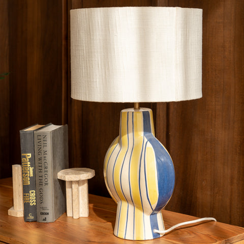 Close-up of the striped table lamp styled next to books on a wooden console.
