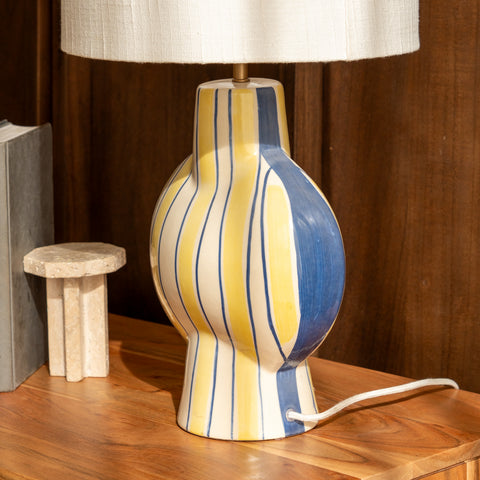 Close-up profile of the yellow and blue striped lamp base on a wooden tabletop.
