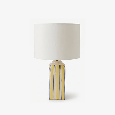 Studio shot of the yellow and blue striped ceramic table lamp on a white background.