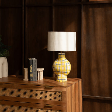 Plaid table lamp illuminating a dark wooden interior setting.
