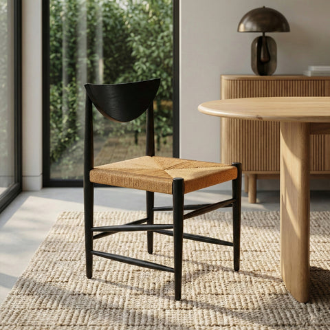 A modern dining chair with a black wood frame, a crescent-shaped backrest, and a woven tan cord seat.