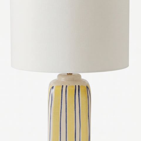 Close-up profile of the yellow and blue striped lamp base on a wooden tabletop.