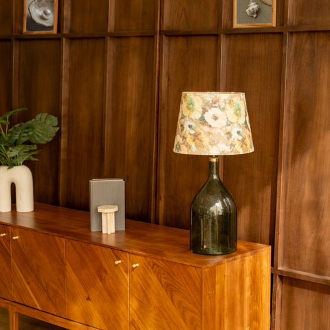Green bottle lamp on a modern wooden sideboard in a living room setting.