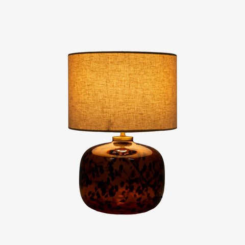 Studio shot of the tortoiseshell lamp with its drum shade fully illuminated.