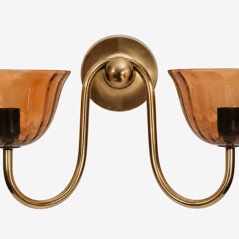Close-up product shot of the brass mount and amber glass sconce shades.