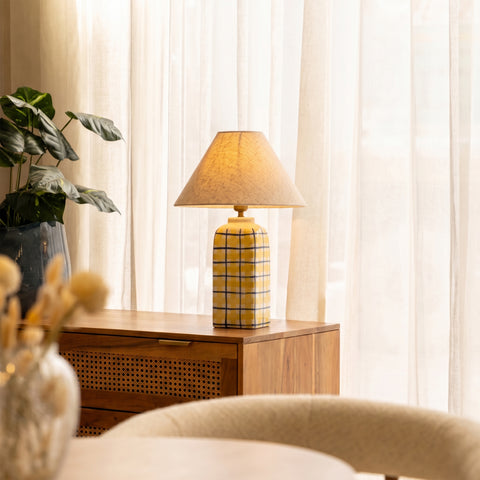 Striped ceramic lamp styled on a wooden dresser next to a small plant.