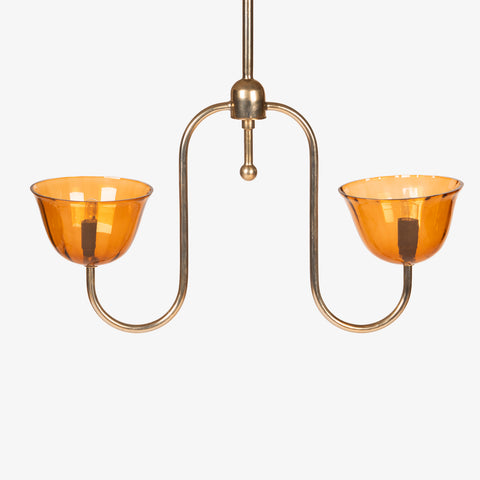 Front-facing studio shot of the brass pendant fixture with unlit amber shades.