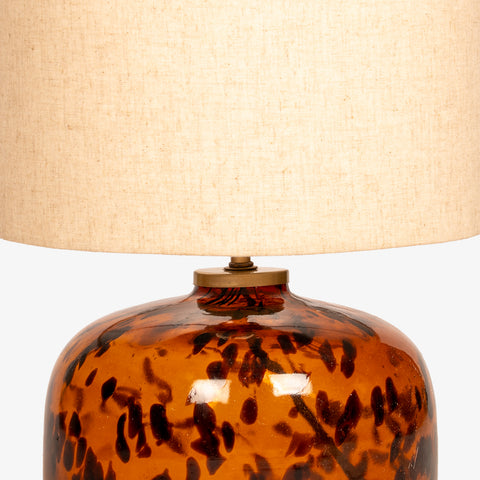 Close-up detail of the glossy tortoiseshell glass base and brass hardware.