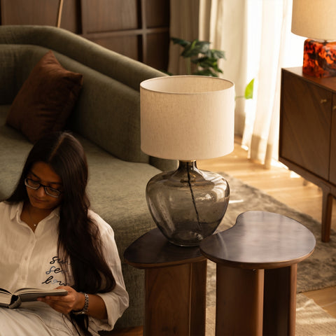 Overhead view of a person reading near the smoky glass table lamp.