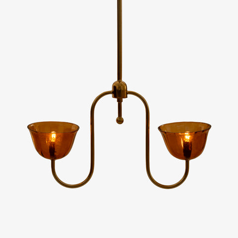 Studio shot of the brass pendant chandelier with its amber shades illuminated.