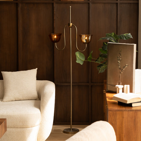 Brass floor lamp next to a cream armchair.