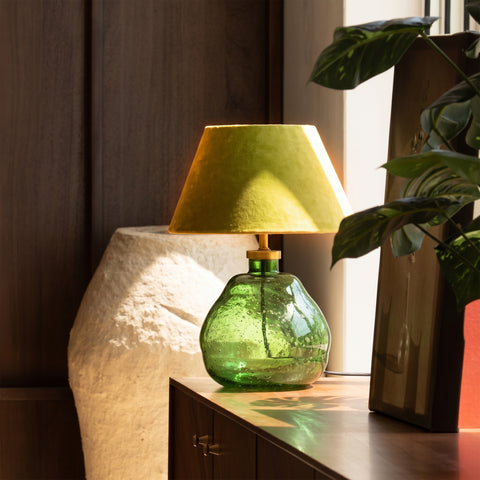 Illuminated green table lamp casting light in a modern living room setting.