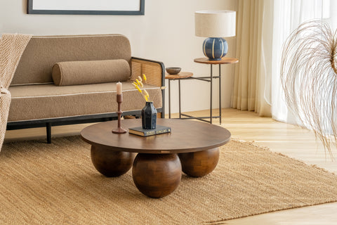 Living room with a brown sofa, round wooden coffee table, and decorative elements.