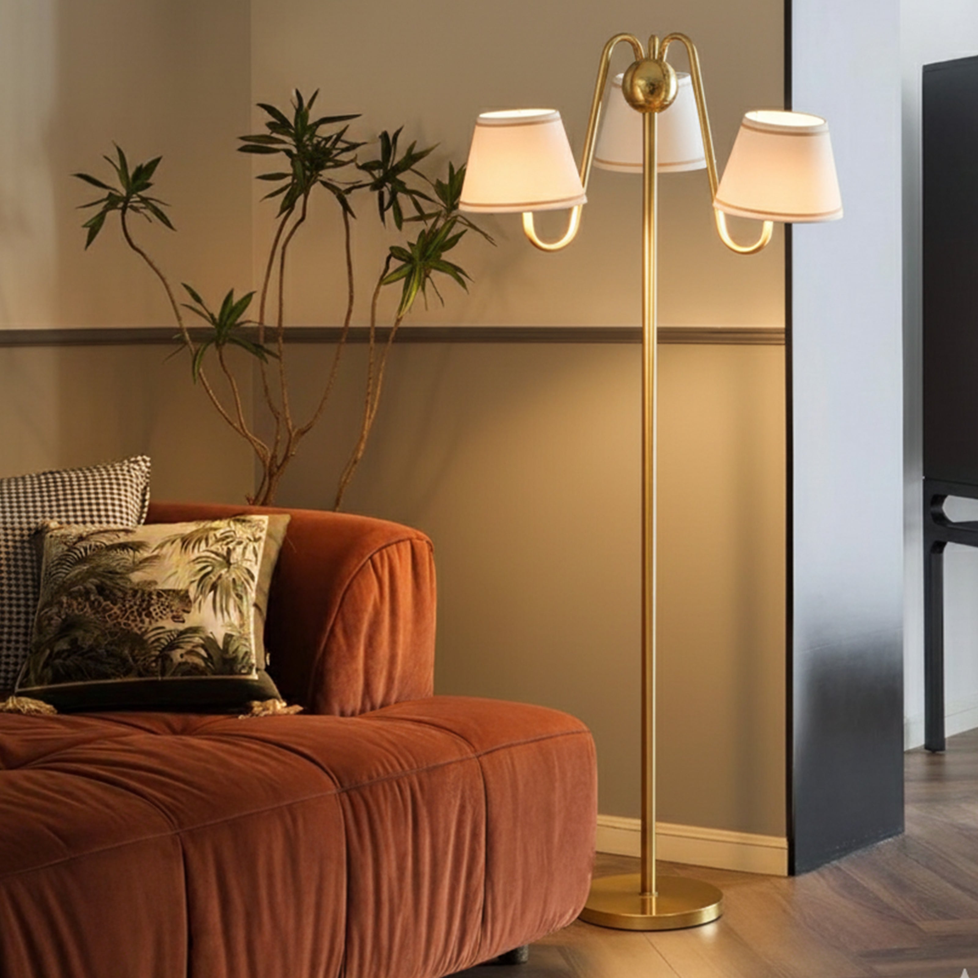 An elegant gold floor lamp with three white pleated shades styled next to a velvet sofa, suitable for floor lamps for living room.