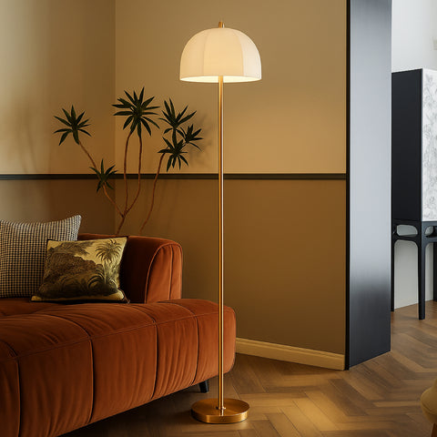 Modern brass floor lamp with dome fabric shade placed beside a sofa in a warm living room interior.