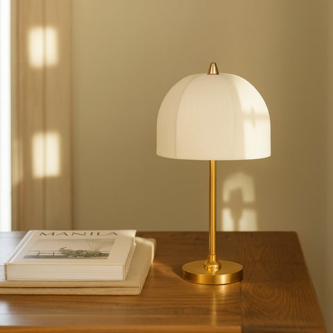 Brass table lamp with fabric dome shade styled on wooden bedside table