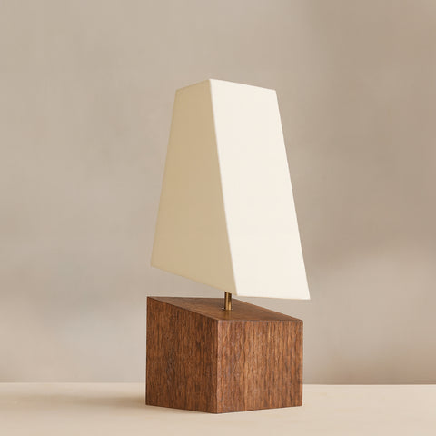 A rustic wood-base side table lamp with a white fabric shade in a warm setting.