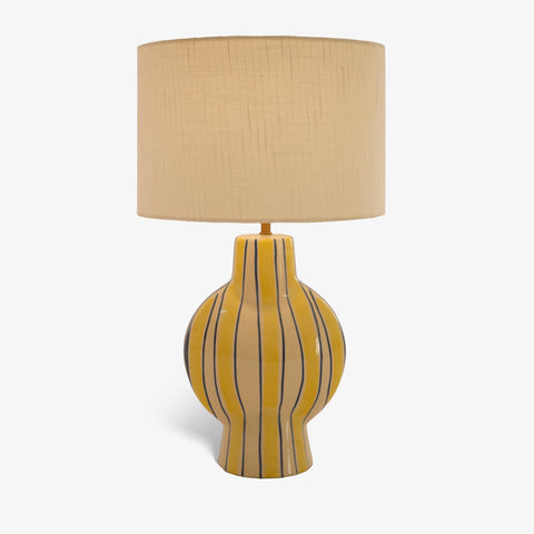 Studio shot of the striped ceramic table lamp with a tan shade against a white background.