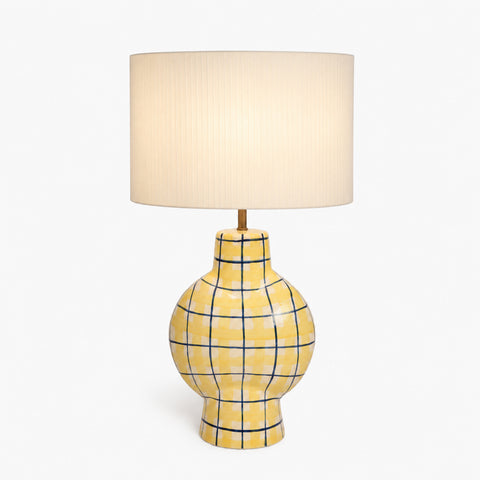ellow ceramic lamp on a wooden dresser in a dimly lit modern room.