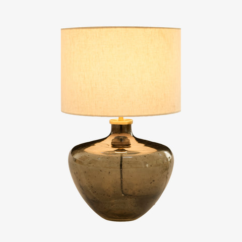 Studio shot of the smoky glass lamp with its drum shade illuminated.