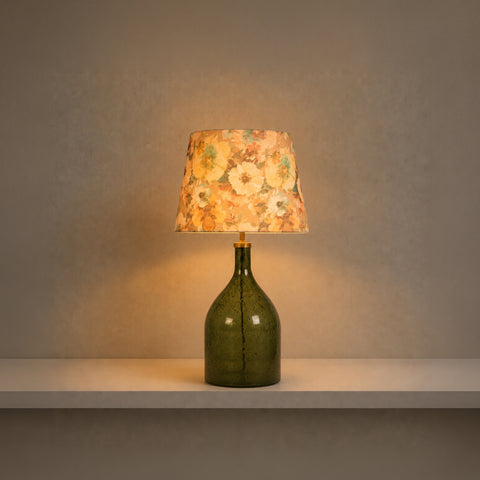 Illuminated glass bottle lamp casting a warm glow on a shelf.