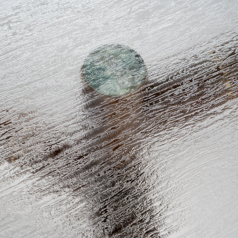 A top-down macro shot focusing on the rippled texture of the green glass surface.