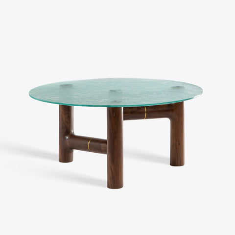 A front-facing studio shot of the round coffee table with a green glass top and wooden legs.