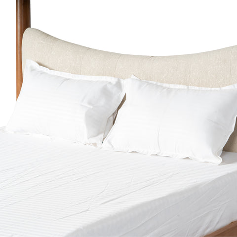 Close-up of white pillows and mattress on a wooden bed.
