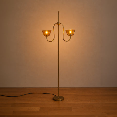 Lit brass floor lamp in a dimly lit room.