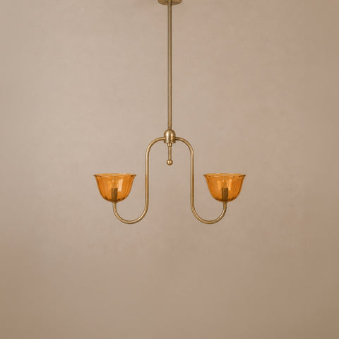 Unlit brass pendant light with two curved arms and amber glass shades.