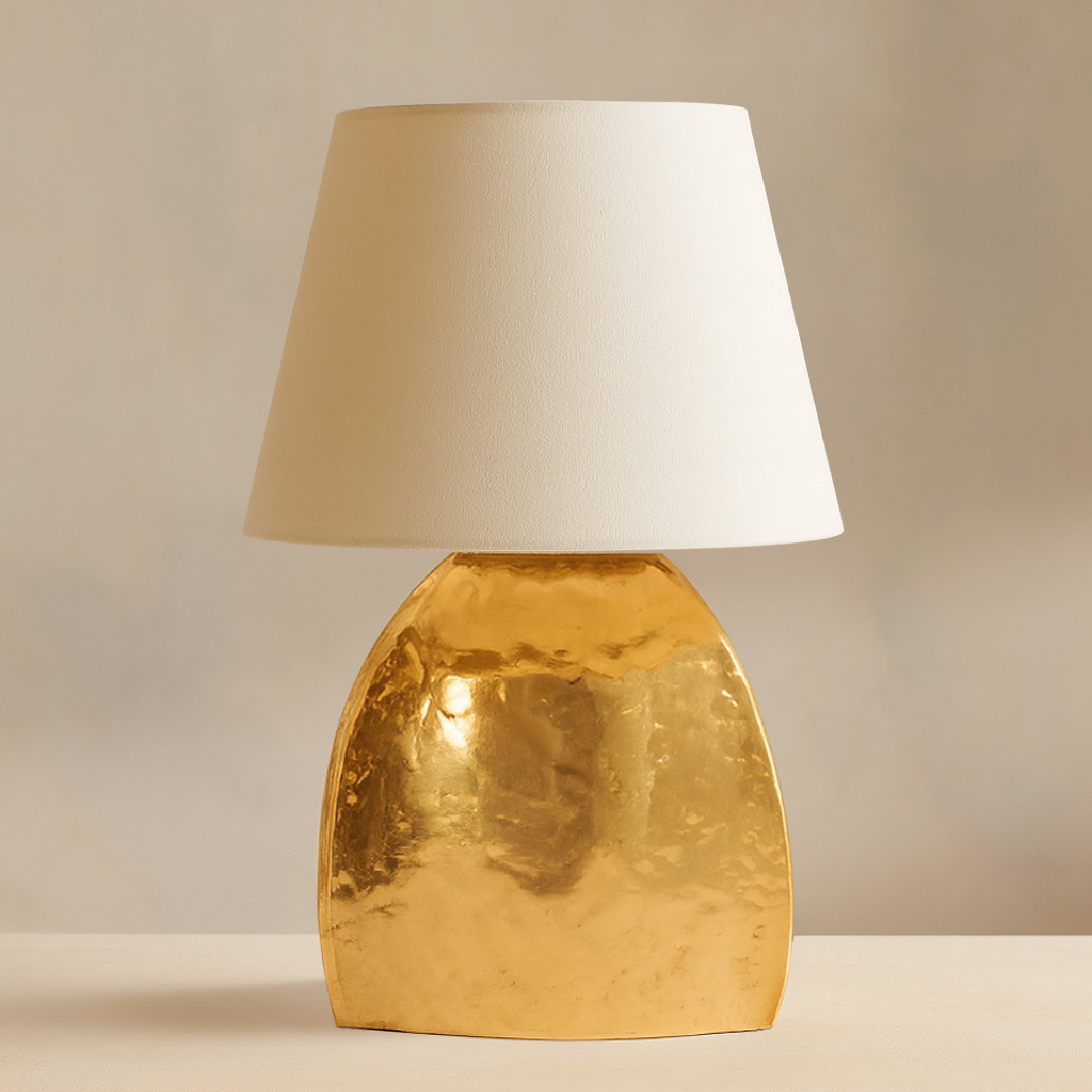 Modern gold table lamp with sculpted metal base and white fabric shade