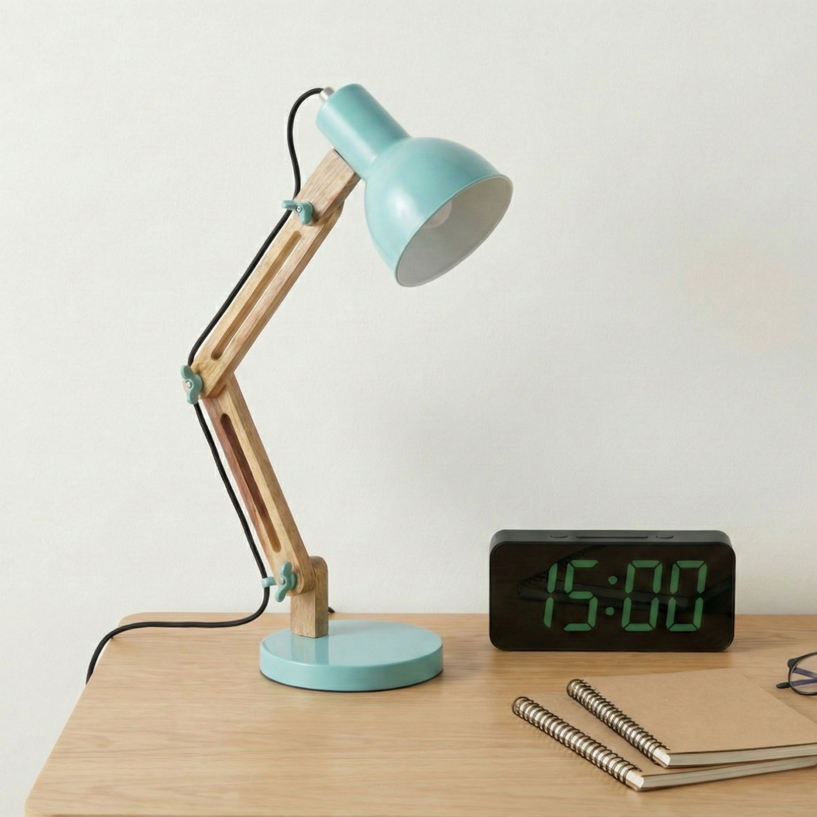 A small adjustable desk lamp with a mint-green shade on a wooden desk.