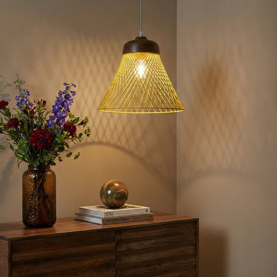 Yellow wire pendant light hanging above a wooden sideboard with flowers and books.