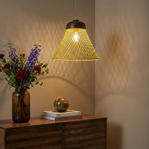 Yellow wire pendant light hanging above a wooden sideboard with flowers and books.