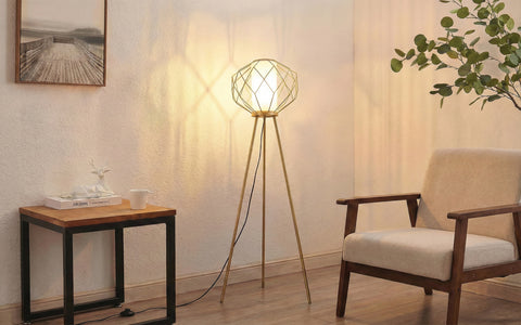 Gold tripod floor lamp with a geometric wire cage and frosted diffuser.