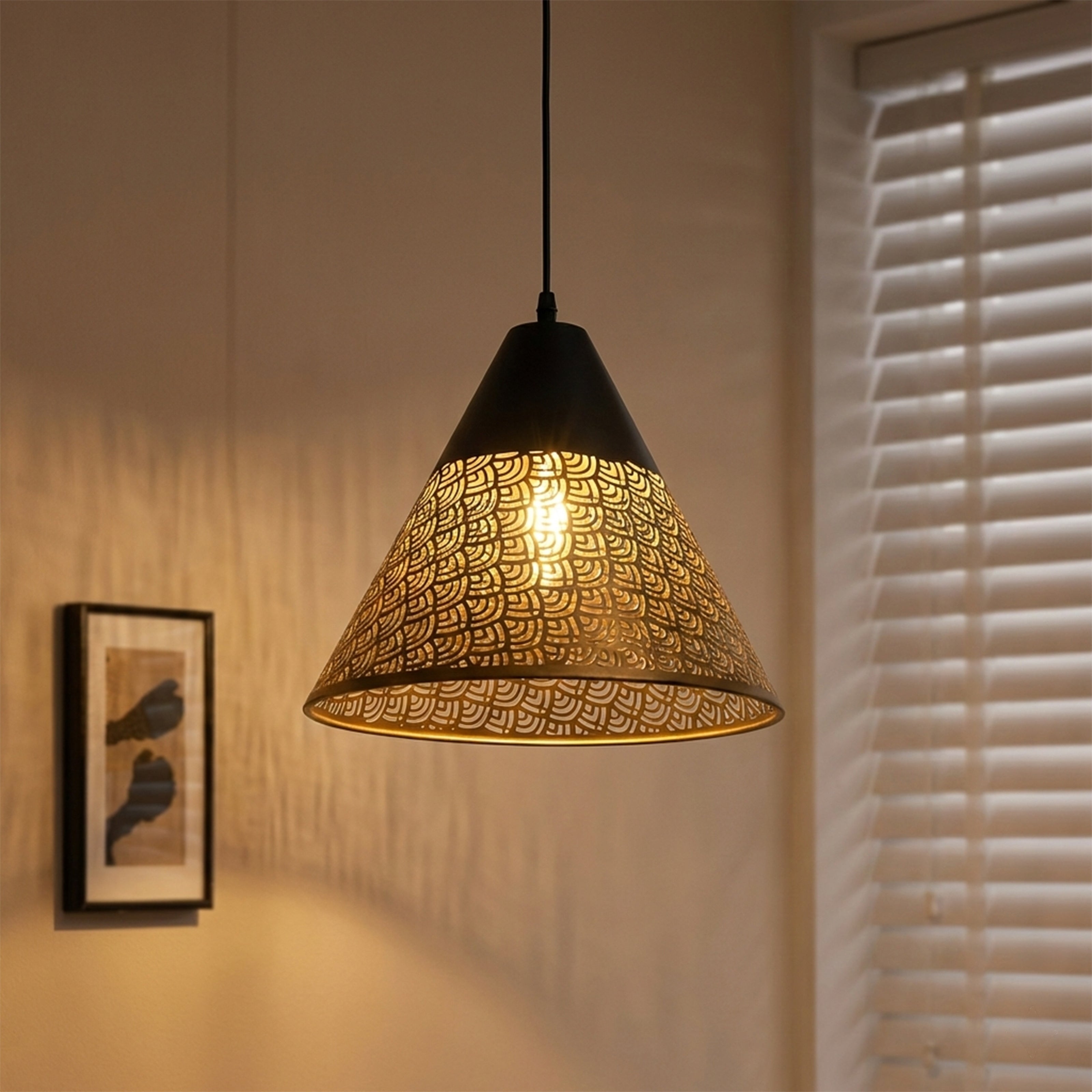 A cone-shaped pendant lamp with a perforated metal shade casting warm patterned light.