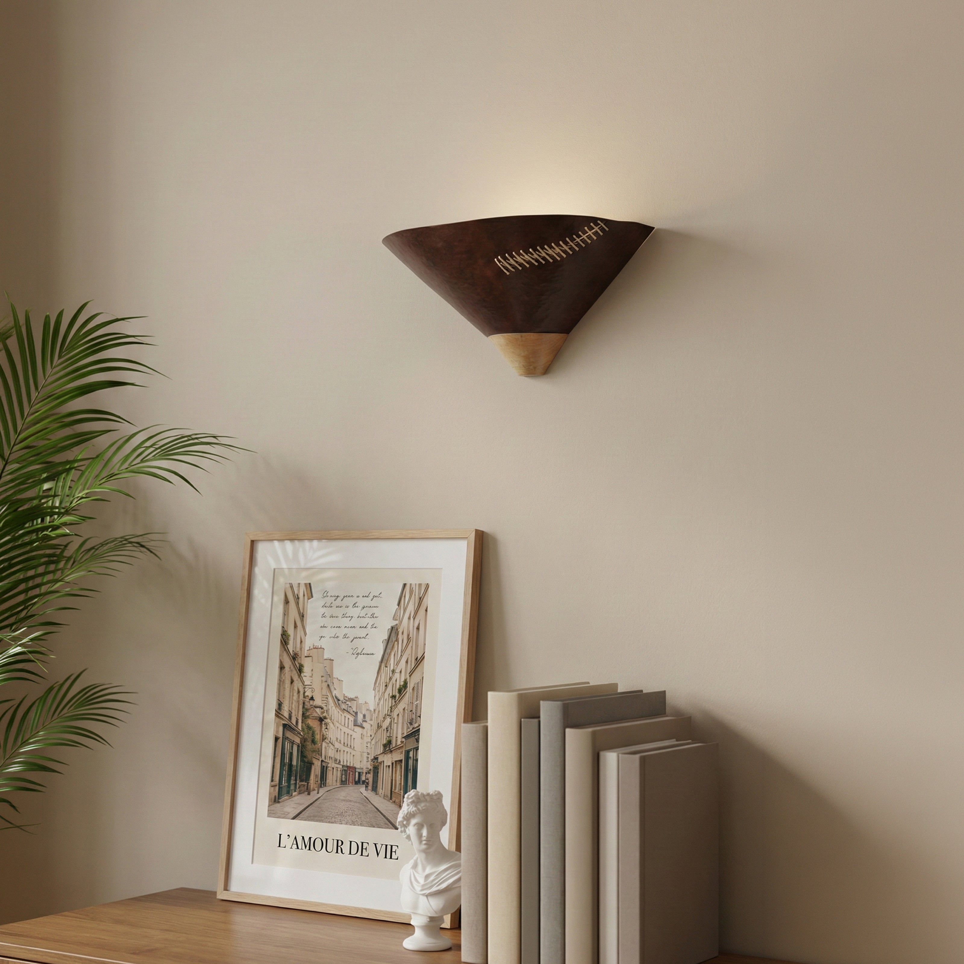 A triangular dark wood wall sconce with decorative cross-stitching mounted above a console table