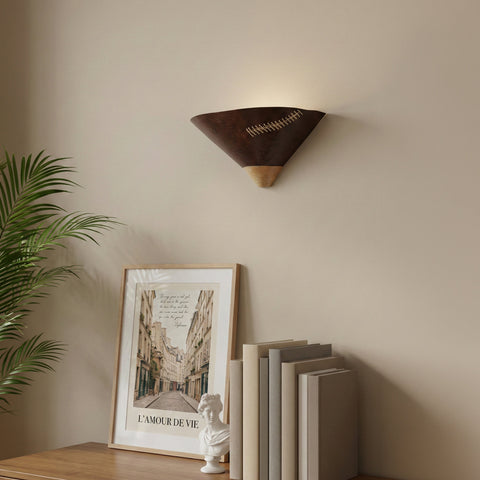 A triangular dark wood wall sconce with decorative cross-stitching mounted above a console table
