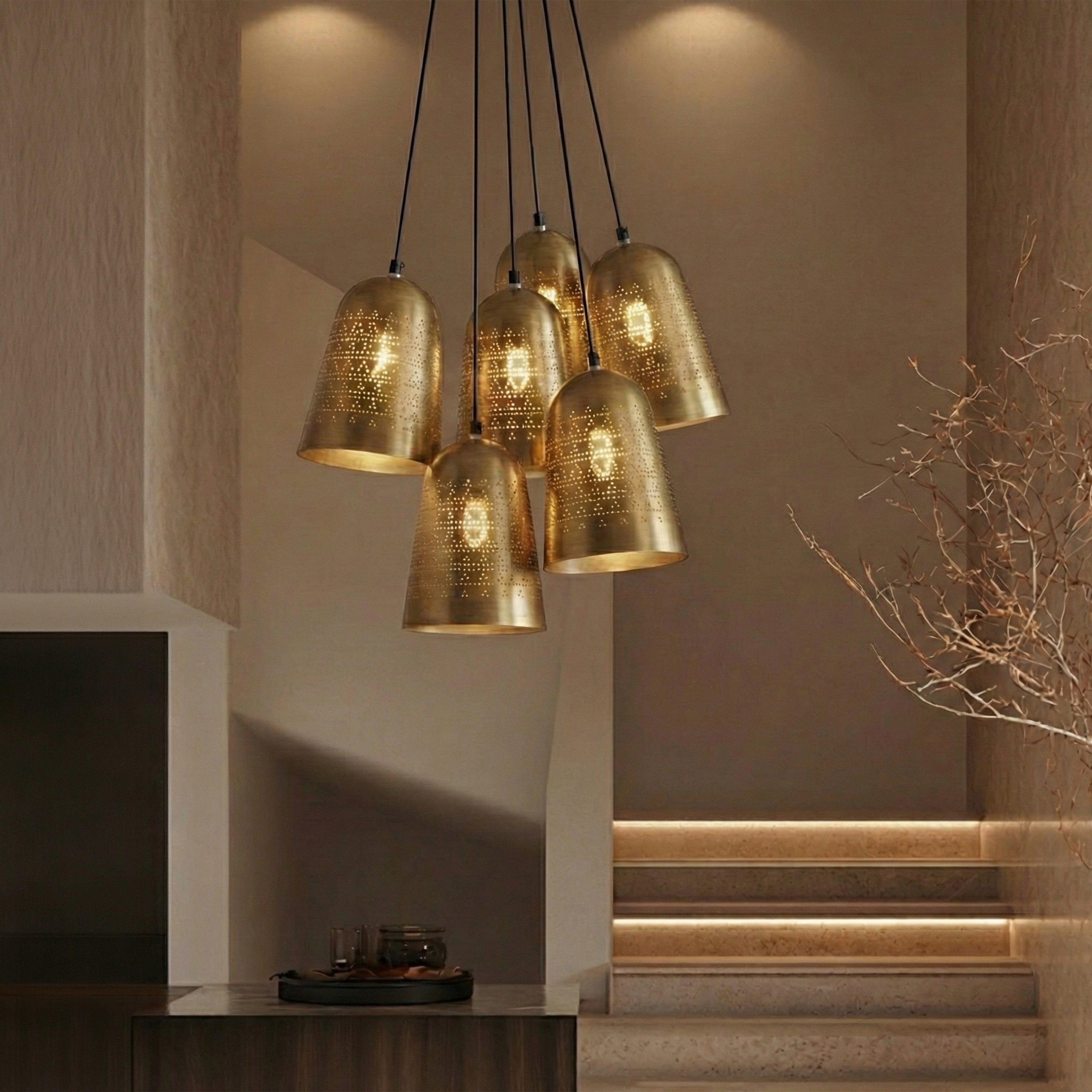 A multi-light cluster pendant featuring seven perforated brass bell shades suspended over a staircase.