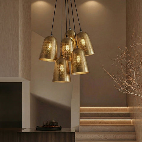 A multi-light cluster pendant featuring seven perforated brass bell shades suspended over a staircase.