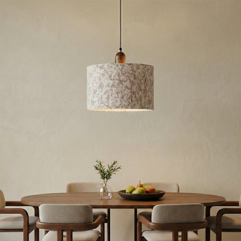Fabric pendant light above a wooden dining table with neutral chairs.