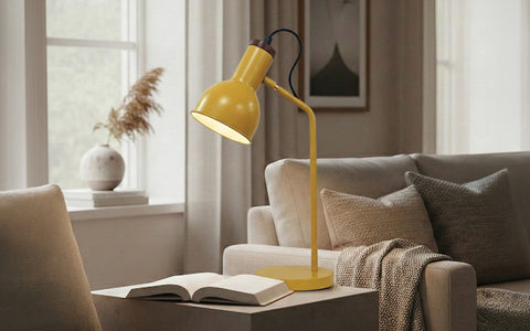Matte yellow adjustable desk lamp on a side table next to a book.