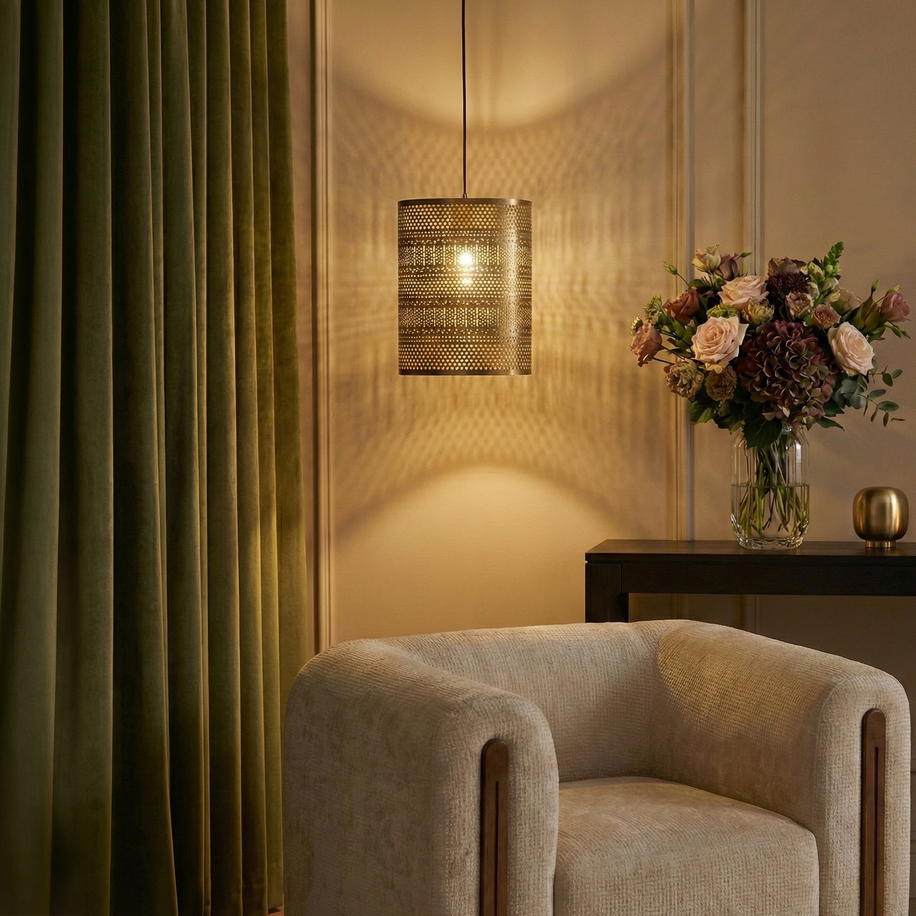 Brass perforated pendant light casting patterned shadows above a lounge chair.