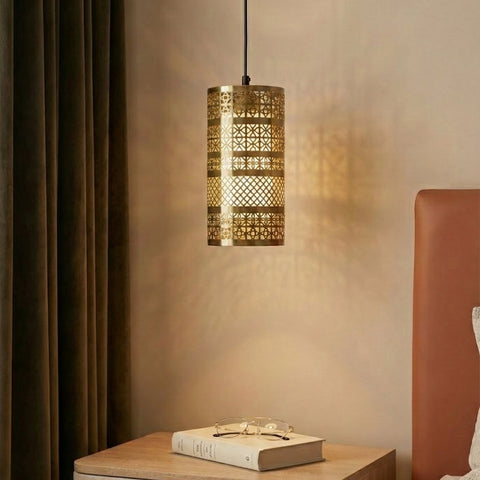 A warm pendant light hangs beside a bed over a wooden nightstand with a book and glasses.