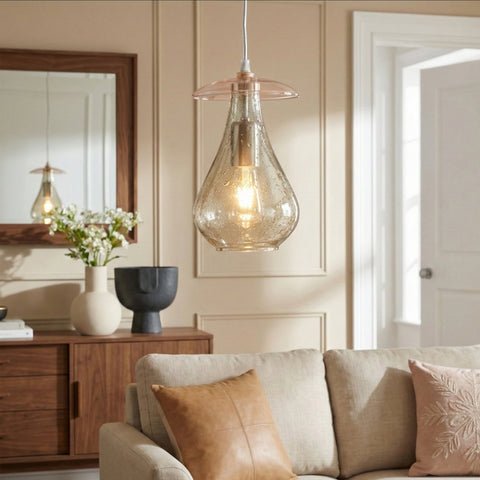 A teardrop-shaped seeded glass pendant light with a pink glass accent hanging in a modern living room