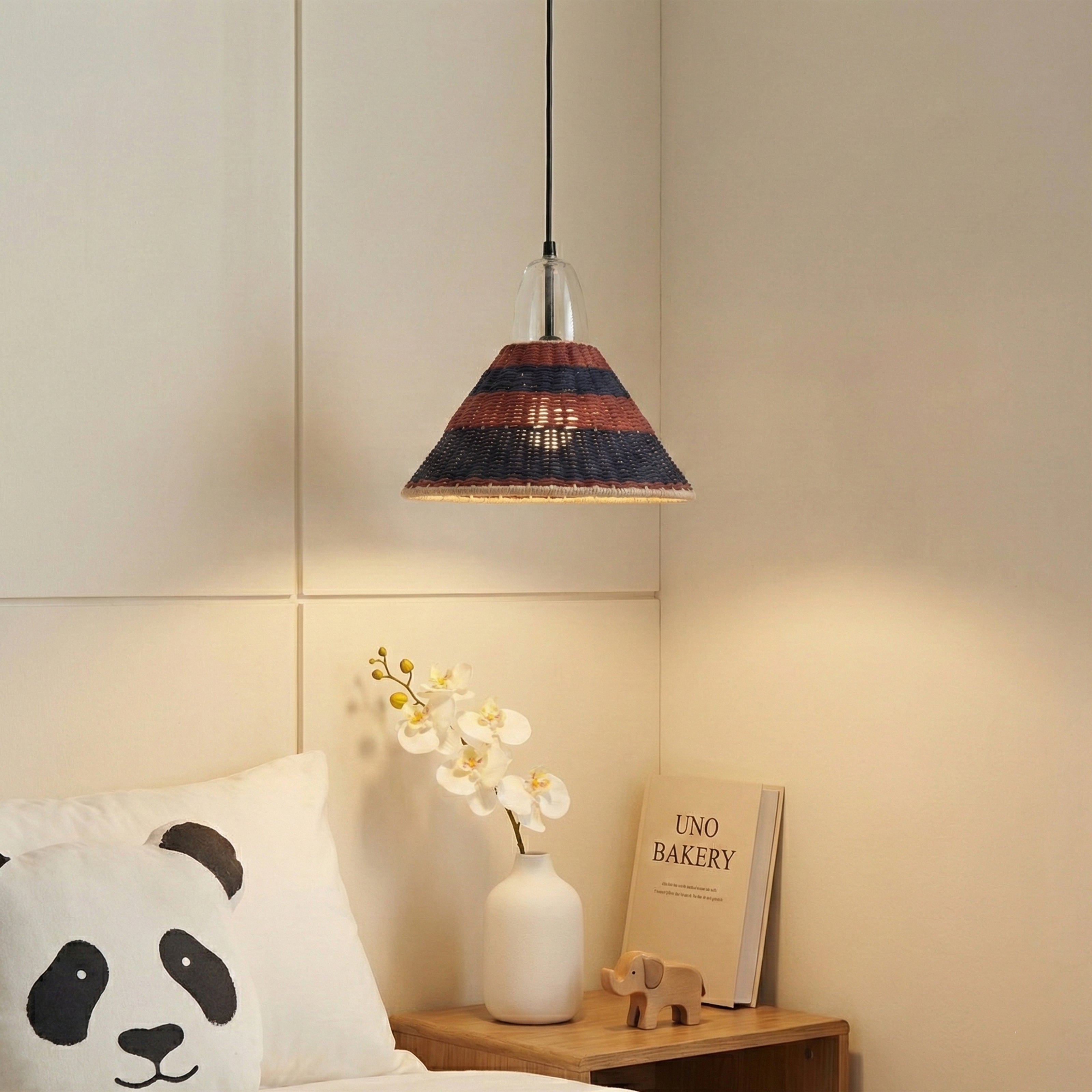 A small conical pendant light with a navy and rust-colored woven shade hanging in a bedroom.