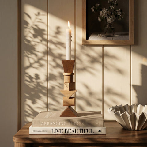 Geometric wooden candle holder on stacked design books with soft sunlight