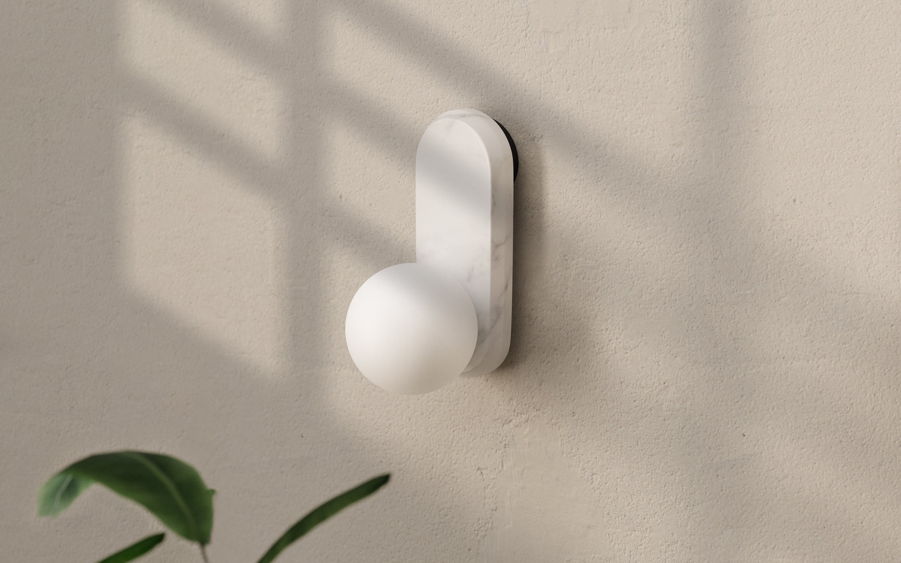 Modern wall lamp with marble base and frosted round bulb, casting gentle light in a bright minimalist corner.