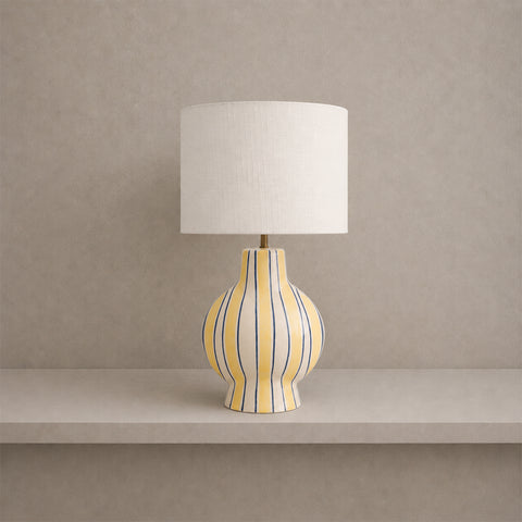 Ceramic table lamp with yellow and blue vertical stripes and a white drum shade.